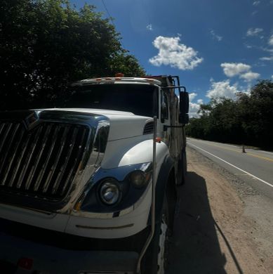 Supervisor de transporte de carga pesada en obra con maquinaria y camión de cantera al fondo